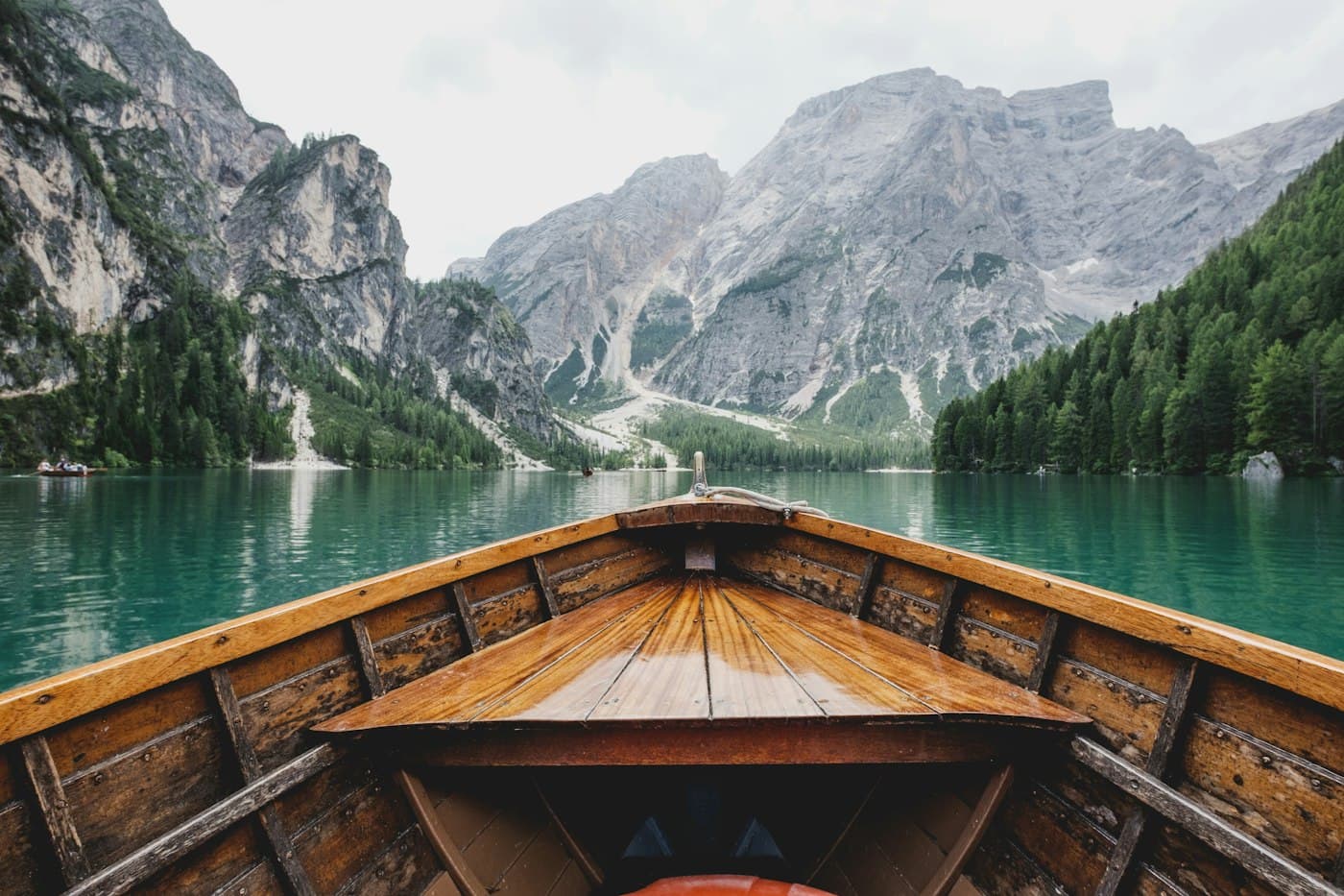 A wooden boat on a clear alpine lake surrounded by mountains