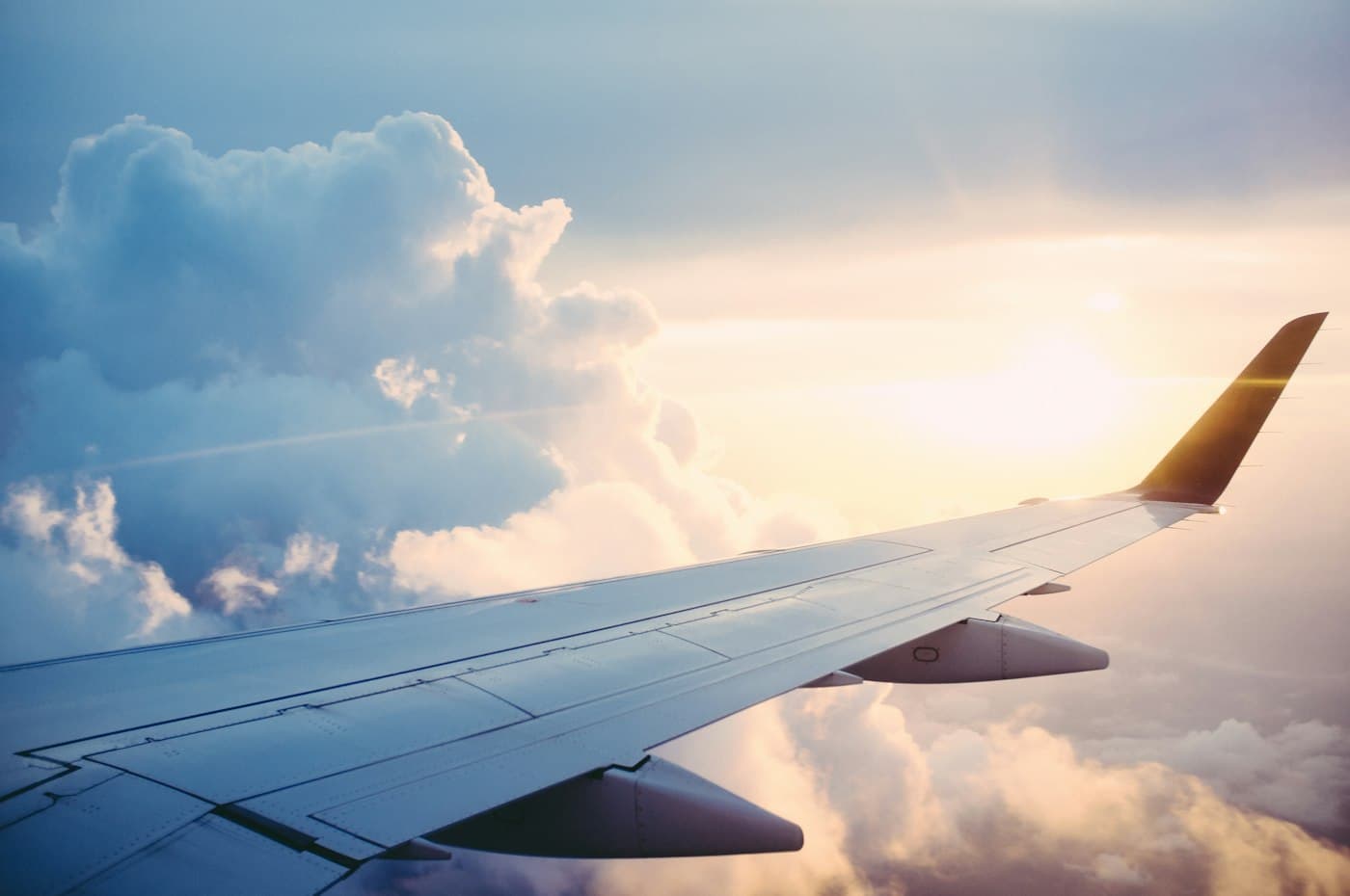 Airplane wing above a sea of clouds at sunset